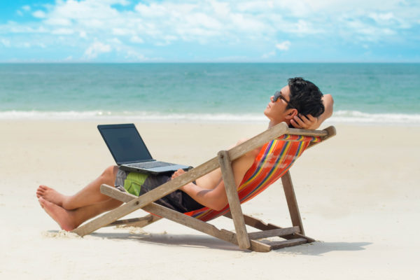 Man entspannt am Strand mit Laptop